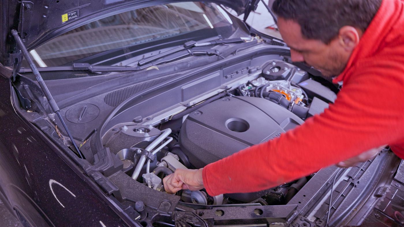 Hicham contrôle le moteur d'un véhicule hybride au garage de Porto-Vecchio